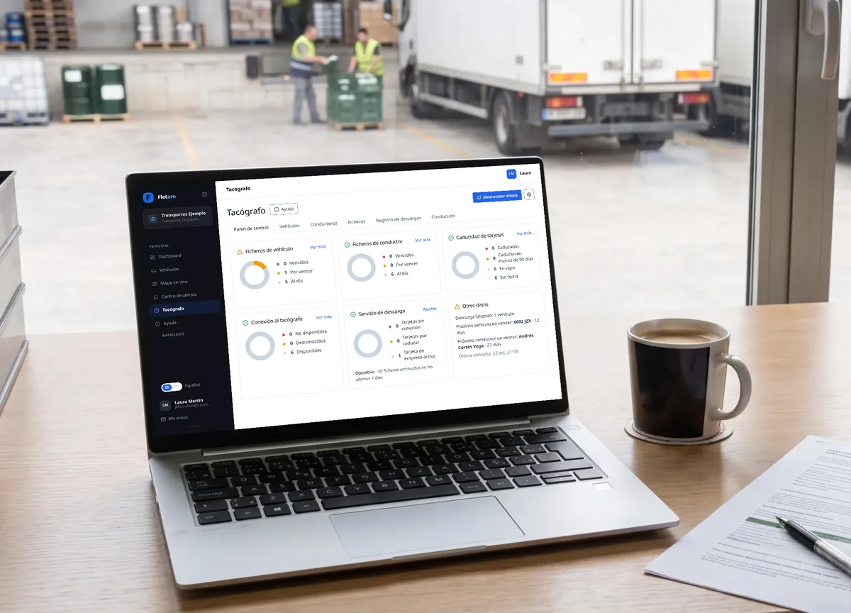 Laptop in a transport company’s traffic office with the Fletaro tachograph dashboard open: 5 of 6 vehicles and 6 of 6 drivers up to date, and a table with each vehicle’s status, the date of the last file, the next deadline, the days left and the reason for the last failure of the only vehicle due soon. The app interface is in Spanish.